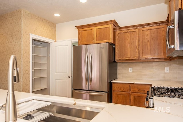 325 S Whisperwood Way, Boise, ID 83709 - kitchen featuring light countertops, brown cabinets, stainless steel appliances, and wallpapered walls