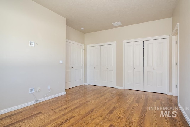 325 S Whisperwood Way, Boise, ID 83709 - unfurnished bedroom with multiple closets, baseboards, and wood finished floors