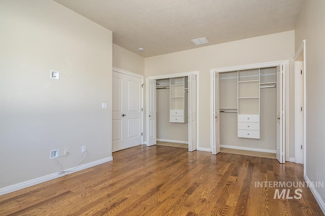 325 S Whisperwood Way, Boise, ID 83709 - unfurnished bedroom with baseboards, multiple closets, wood finished floors, and visible vents