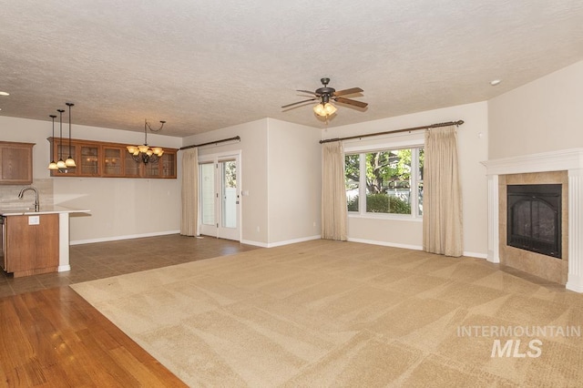 325 S Whisperwood Way, Boise, ID 83709 - unfurnished living room featuring a sink, a textured ceiling, ceiling fan with notable chandelier, baseboards, and a tile fireplace