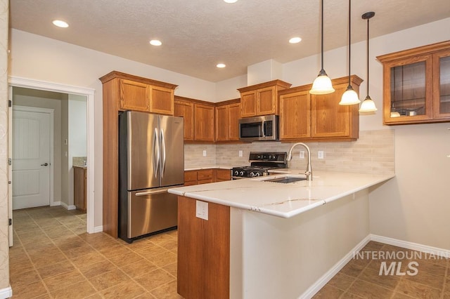 325 S Whisperwood Way, Boise, ID 83709 - kitchen with appliances with stainless steel finishes, a sink, brown cabinetry, a peninsula, and backsplash