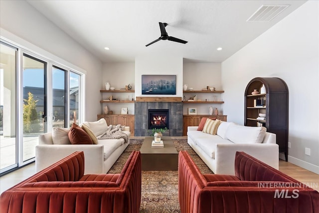 living room featuring ceiling fan, a fireplace, and light hardwood / wood-style floors