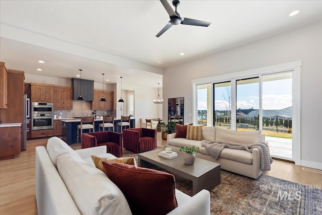 living room with a mountain view, ceiling fan with notable chandelier, and light wood-type flooring