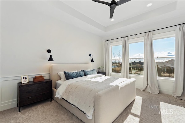 carpeted bedroom featuring a raised ceiling and ceiling fan