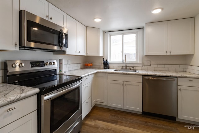 kitchen featuring dark wood-style floors, appliances with stainless steel finishes, white cabinets, and a sink