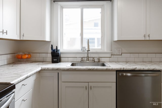 kitchen with stainless steel appliances, light stone counters, a sink, and white cabinets