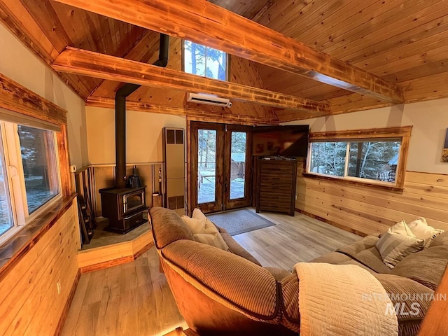 living room featuring light hardwood / wood-style floors, a wood stove, wooden walls, and wood ceiling