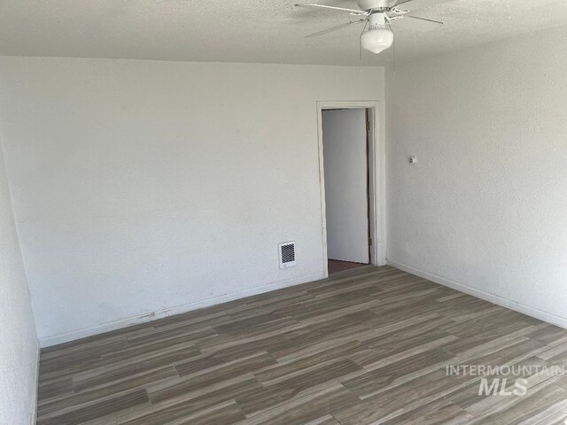 empty room featuring baseboards, wood finished floors, visible vents, and ceiling fan