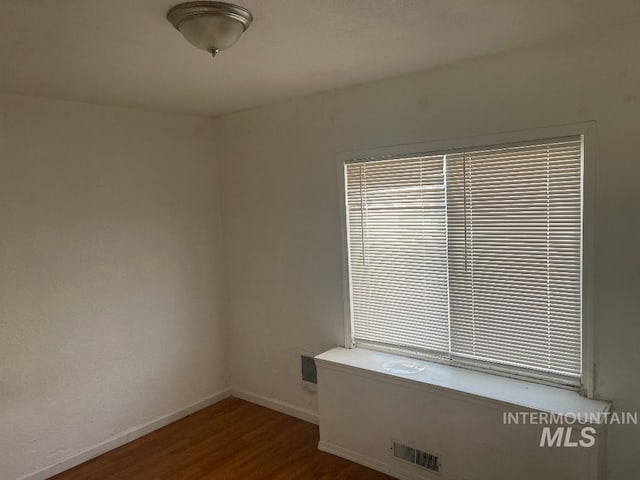 unfurnished room with wood finished floors, visible vents, and baseboards