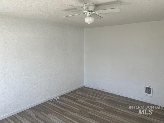 spare room with baseboards, visible vents, ceiling fan, and dark wood finished floors