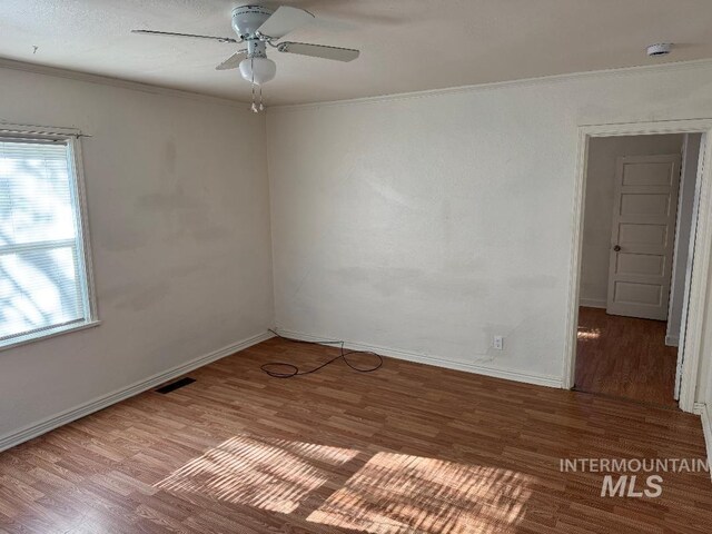 unfurnished room with wood finished floors, visible vents, and ornamental molding