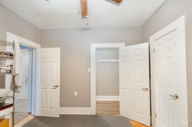 unfurnished bedroom featuring a ceiling fan, light wood-style flooring, baseboards, and a textured ceiling