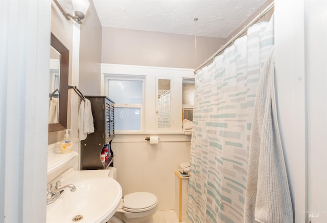 bathroom with toilet, a shower with curtain, tile patterned floors, a textured ceiling, and a sink