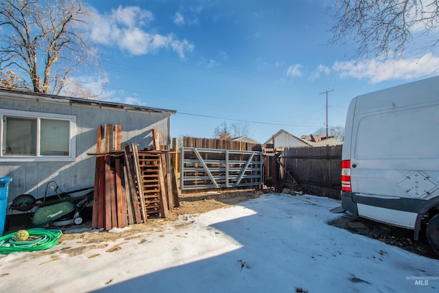 snowy yard featuring a gate and fence