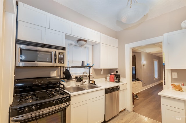 kitchen with a sink, white cabinetry, stainless steel appliances, and light countertops