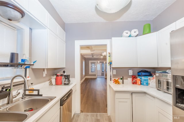 kitchen featuring light wood-style flooring, a sink, white cabinets, light countertops, and appliances with stainless steel finishes