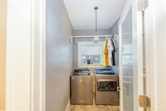 laundry area featuring light wood-type flooring, laundry area, baseboards, and separate washer and dryer