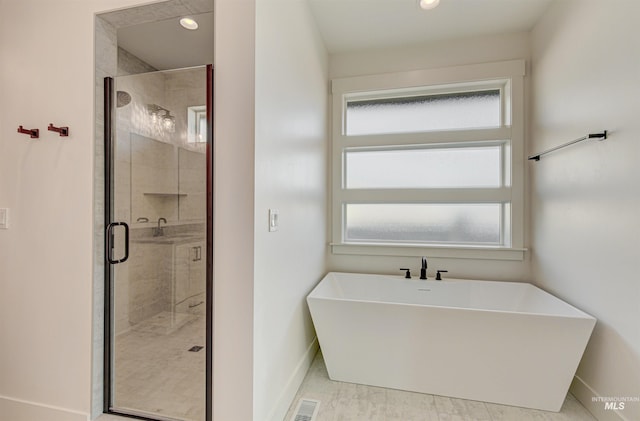 bathroom with a shower stall, a freestanding tub, visible vents, and baseboards