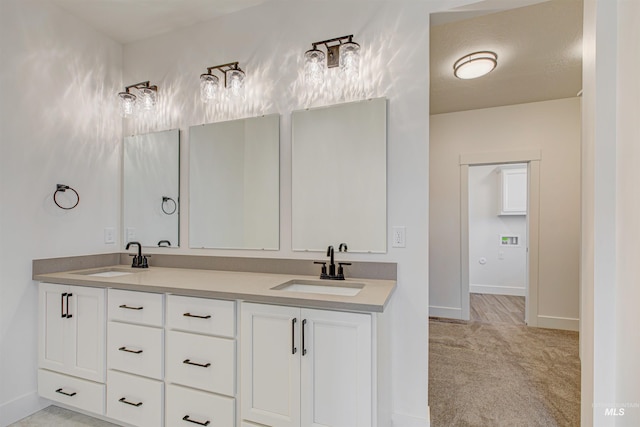 full bathroom featuring a sink, baseboards, and double vanity