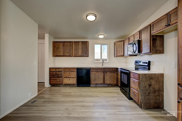 kitchen featuring black appliances, sink, and light hardwood / wood-style flooring