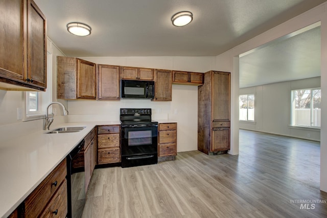 kitchen with black appliances, lofted ceiling, sink, and light hardwood / wood-style flooring