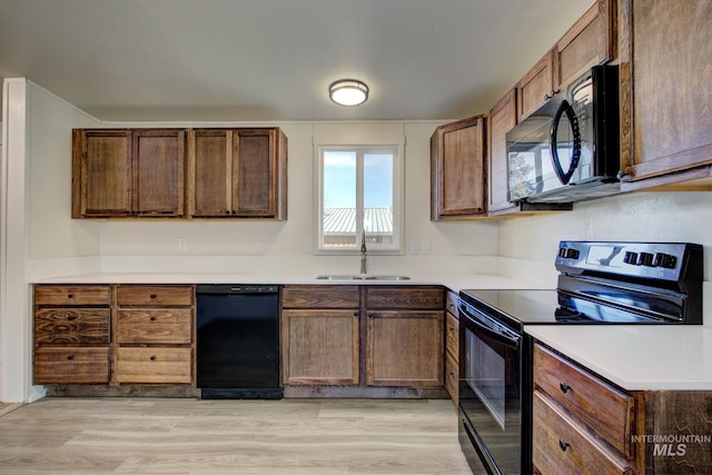 kitchen featuring sink, light hardwood / wood-style flooring, and black appliances