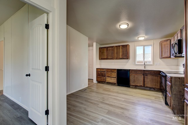 kitchen with black appliances, sink, and light hardwood / wood-style flooring