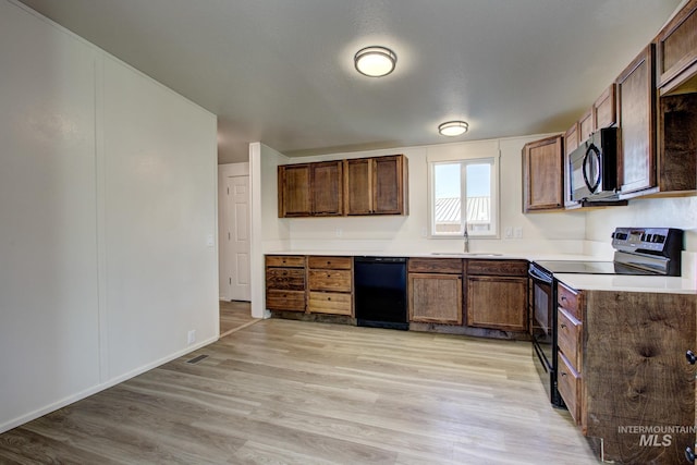 kitchen with light wood-type flooring, a textured ceiling, sink, and black appliances