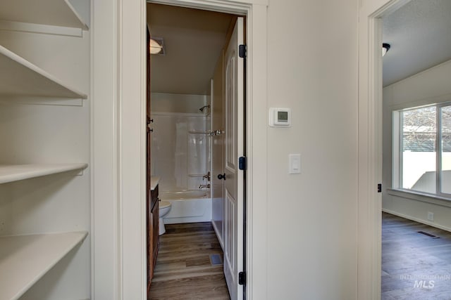 bathroom with hardwood / wood-style floors,  shower combination, and toilet