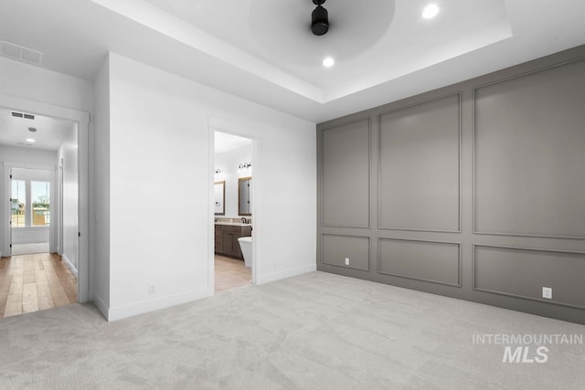 2716 N Heirloom Ave, Eagle, ID 83616 - unfurnished bedroom featuring a decorative wall, connected bathroom, light colored carpet, a raised ceiling, and baseboards