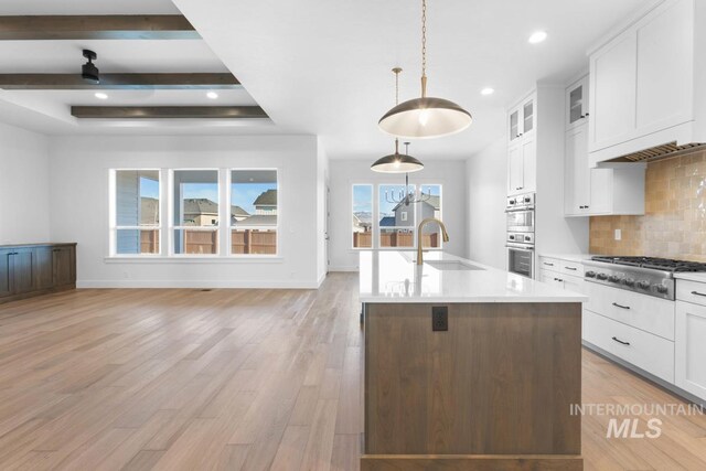 2716 N Heirloom Ave, Eagle, ID 83616 - kitchen with baseboards, light wood-style flooring, backsplash, white cabinets, and stainless steel appliances