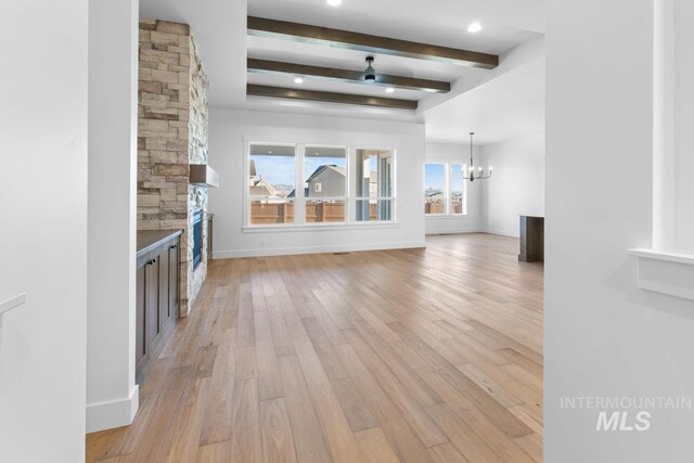 2716 N Heirloom Ave, Eagle, ID 83616 - unfurnished living room with light wood-type flooring, baseboards, a chandelier, a fireplace, and beamed ceiling