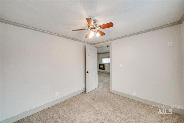 empty room with ceiling fan, light colored carpet, ornamental molding, and a textured ceiling