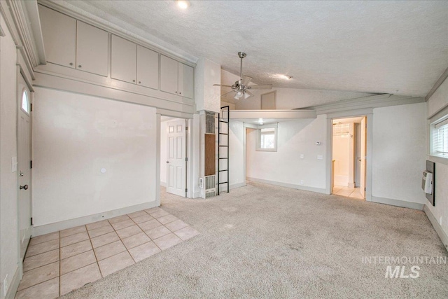 basement with a textured ceiling, light colored carpet, and ceiling fan