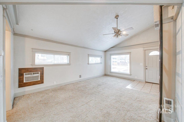 entryway with a textured ceiling, a wealth of natural light, light colored carpet, and vaulted ceiling