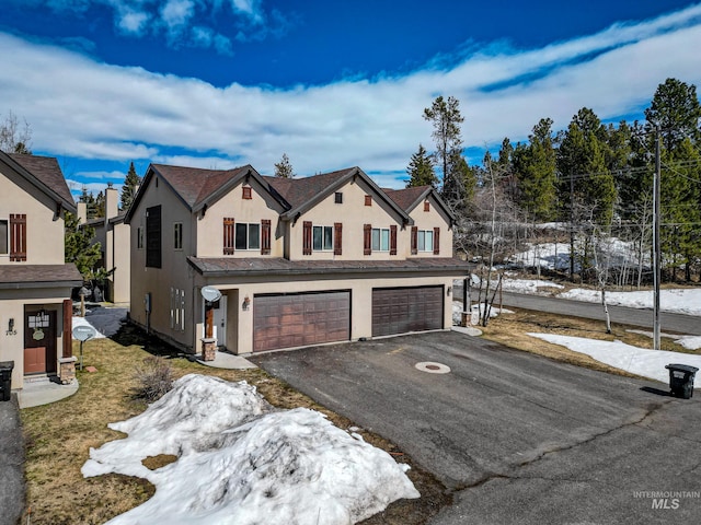 view of front of property with aphalt driveway, an attached garage, and stucco siding