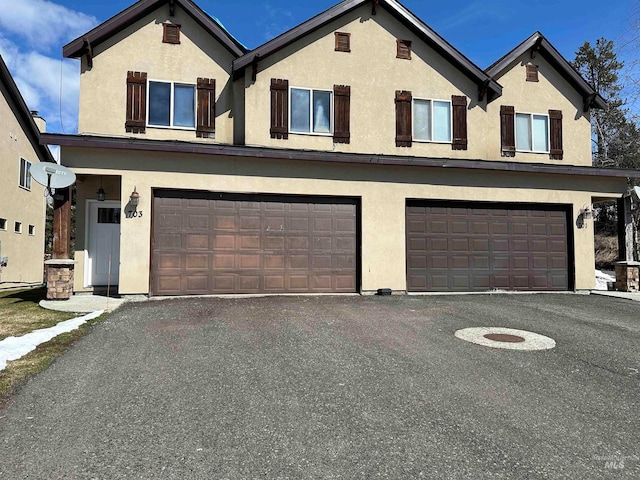 view of front of house featuring an attached garage, aphalt driveway, and stucco siding