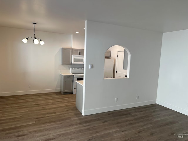 kitchen with dark wood-style flooring, gray cabinets, light countertops, white appliances, and baseboards