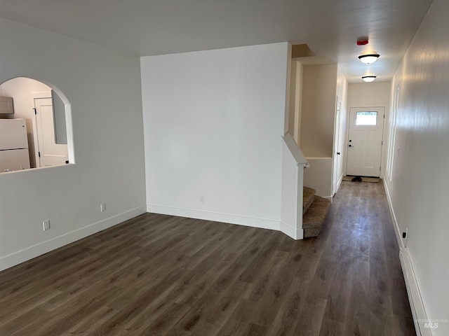 interior space with a baseboard heating unit, dark wood-style flooring, baseboards, and stairs