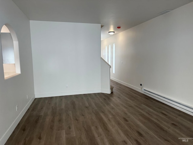 empty room featuring baseboards, visible vents, arched walkways, dark wood-style floors, and baseboard heating