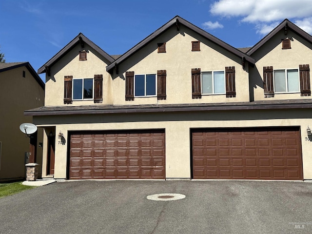 view of front facade featuring aphalt driveway, an attached garage, and stucco siding