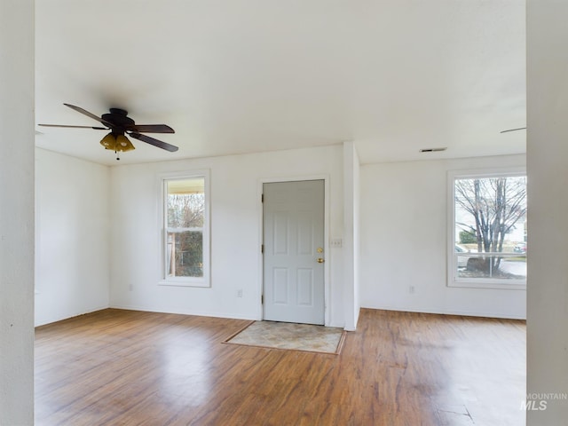 empty room with light wood-style floors, visible vents, and a ceiling fan