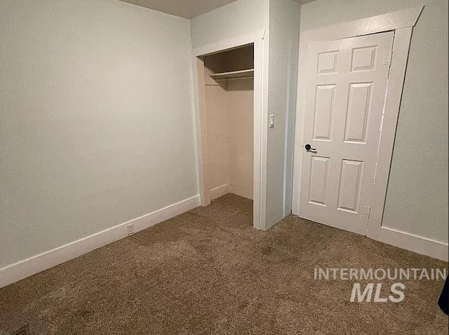 unfurnished bedroom with a closet and dark colored carpet