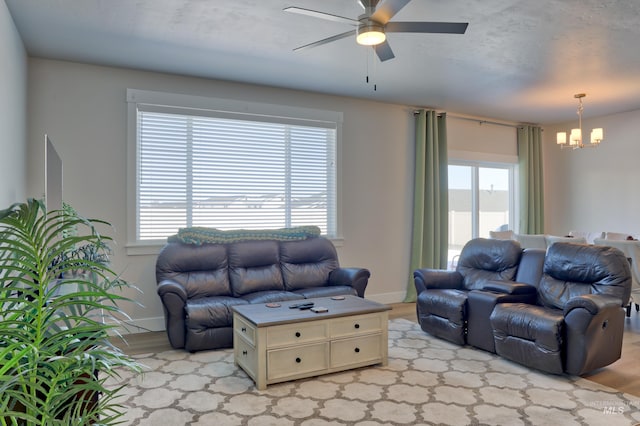 living room with ceiling fan with notable chandelier and light hardwood / wood-style floors