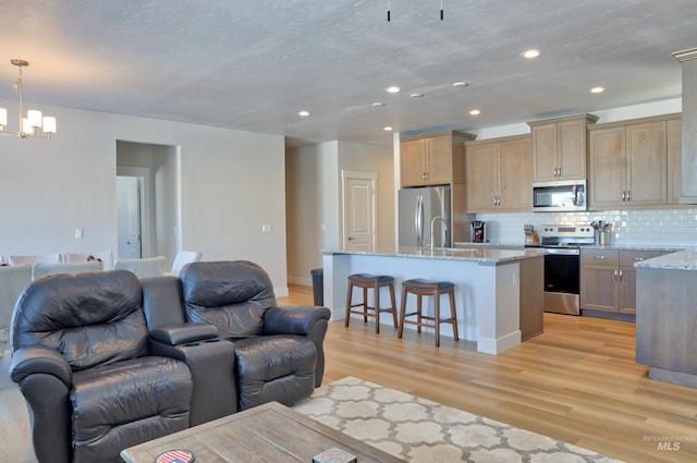 living room with sink, an inviting chandelier, and light wood-type flooring