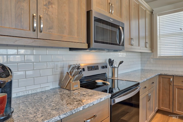 kitchen with appliances with stainless steel finishes, backsplash, and light stone counters