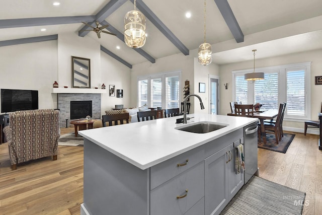 kitchen with gray cabinets, light countertops, light wood-type flooring, a fireplace, and a sink