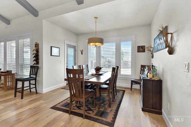 dining room with baseboards, beamed ceiling, and light wood finished floors