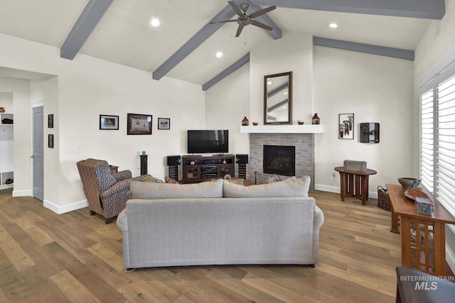 living room with beamed ceiling, a fireplace, wood finished floors, and baseboards