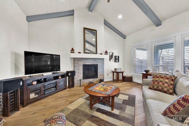 living area featuring high vaulted ceiling, a tile fireplace, baseboards, light wood-style floors, and beam ceiling